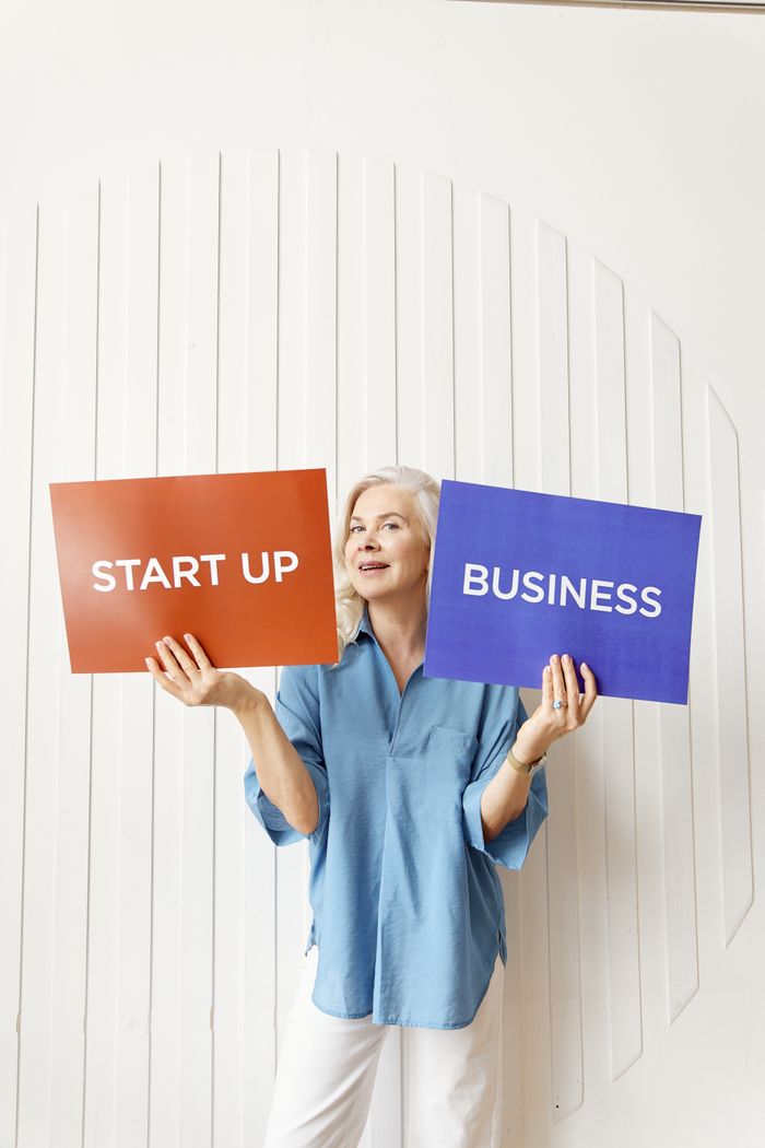 Smiling senior woman entrepreneur holds signs for start-up and business concepts.